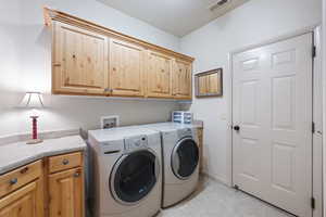 Laundry room with cabinet space, washer and clothes dryer, and light tile patterned floors
