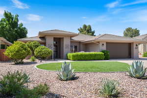 Prairie-style house featuring a front lawn, stucco siding, a tile roof, a garage, and driveway