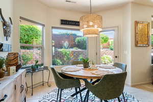 Dining room featuring healthy amount of natural light, light tile patterned flooring, and a chandelier