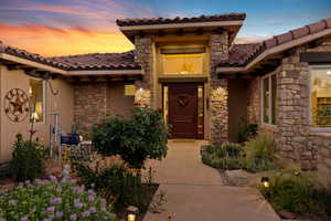 Entrance to property with a tiled roof, stone siding, and stucco siding