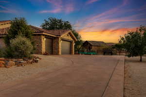 View of front of house featuring stone siding, a garage, a tiled roof, and concrete driveway