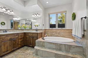 Full bathroom with double vanity, a garden tub, and recessed lighting