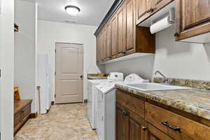 Washroom featuring washer and dryer, cabinet space, and stone finish floors