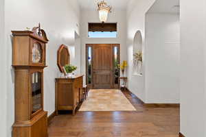 Entrance foyer with wood finished floors and a towering ceiling