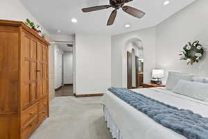 Bedroom featuring arched walkways, light carpet, recessed lighting, and a ceiling fan