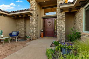 View of exterior entry featuring stone siding and stucco siding