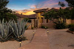Mediterranean / spanish house featuring a tiled roof, stucco siding, stone siding, a gate, and a chimney