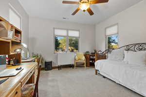 Bedroom featuring light colored carpet, a desk, and a ceiling fan