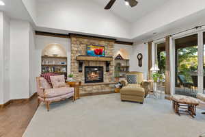 Living area featuring ceiling fan, a fireplace, high vaulted ceiling, and wood finished floors