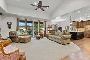Living room featuring ceiling fan, light wood-style flooring, a chandelier, recessed lighting, and high vaulted ceiling