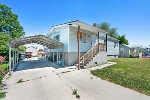 View of front of house with a carport, driveway, a front yard, and a chimney
