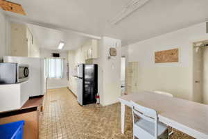 Kitchen with freestanding refrigerator, stainless steel microwave, and white cabinets