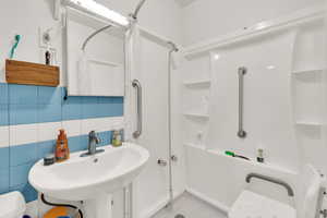 Bathroom featuring a shower, tasteful backsplash, and tile walls