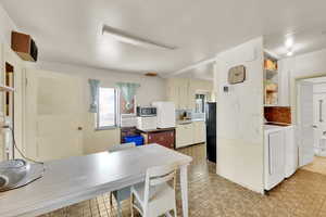 Kitchen with washer and dryer, stainless steel microwave, decorative backsplash, freestanding refrigerator, and light countertops
