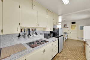 Kitchen featuring stainless steel appliances, light countertops, backsplash, and cream cabinets