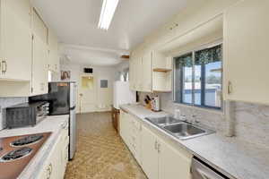 Kitchen featuring healthy amount of natural light, backsplash, light countertops, and appliances with stainless steel finishes