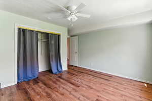 Unfurnished bedroom featuring wood finished floors, a closet, and a ceiling fan