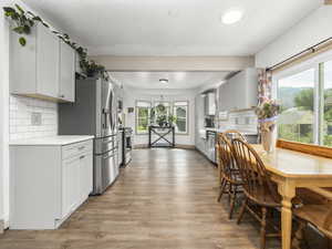 Kitchen with appliances with stainless steel finishes, light countertops, light wood-style floors, and decorative backsplash