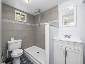 Full bath with a tile shower, tile walls, and vanity