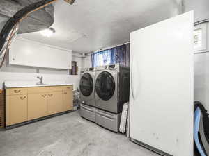 Washroom with separate washer and dryer, cabinet space, and a textured ceiling