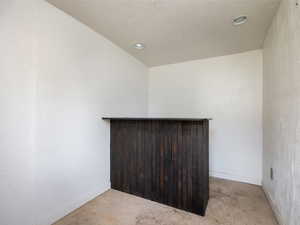 Unfurnished room featuring a dry bar, recessed lighting, and concrete flooring