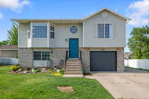 Raised ranch featuring a garage, driveway, and brick siding