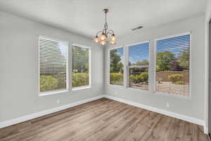Unfurnished room with a chandelier and wood finished floors