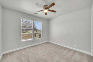 Empty room featuring a ceiling fan and light colored carpet