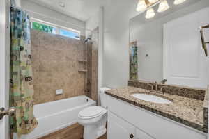 Full bath featuring shower / tub combo with curtain, vanity, and wood finished floors