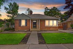 Bungalow-style home with a chimney, brick siding, and roof with shingles