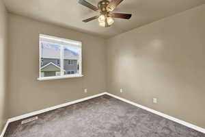 Carpeted empty room with baseboards and a ceiling fan