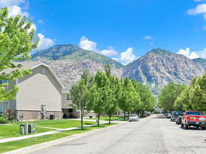 View of asphalt street with sidewalks, a mountain view, curbs, and a residential view