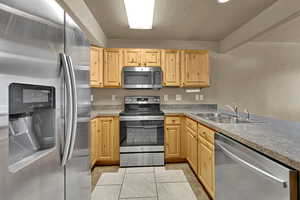 Kitchen featuring stainless steel appliances, light brown cabinetry, and light tile patterned floors