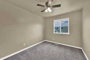 Unfurnished room with dark colored carpet and ceiling fan