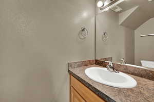 Half bathroom with vanity and a textured wall