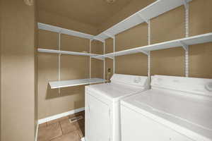 Washroom featuring washing machine and clothes dryer and light tile patterned floors