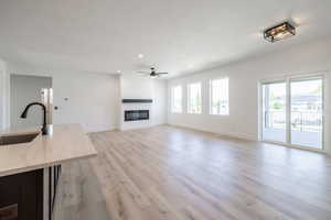 Unfurnished living room featuring a textured ceiling, healthy amount of natural light, recessed lighting, light wood-style flooring, and ceiling fan