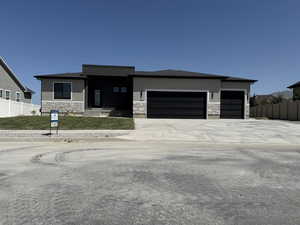 View of front of property featuring stone siding, an attached garage, stucco siding, and driveway