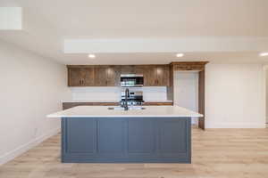 Kitchen featuring stainless steel microwave, light countertops, recessed lighting, stove, and light wood-style floors