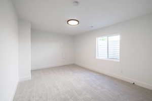 Carpeted spare room featuring baseboards and a smoke detector