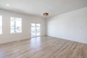Empty room with light wood-type flooring, a textured ceiling, and recessed lighting