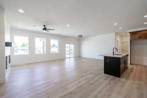 Unfurnished living room featuring recessed lighting, plenty of natural light, a ceiling fan, and light wood-style floors