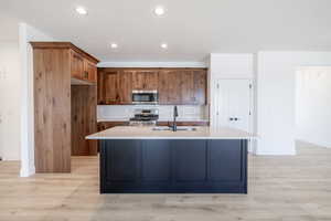 Kitchen featuring stainless steel appliances, light wood-style flooring, light countertops, decorative backsplash, and recessed lighting