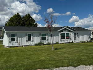 Manufactured / mobile home with board and batten siding, a front yard, and roof with shingles