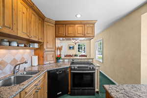 Kitchen featuring black dishwasher, electric range oven,  appliance garage and over the sink lighting with dimmer