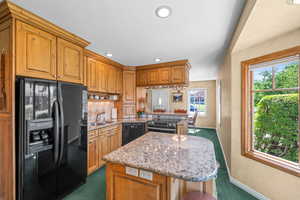 Kitchen featuring black appliances, Refrigerator with water and ice dispenser,  healthy amount of natural light, a center island, and recessed lighting
