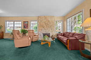 Living room featuring hardwood floors under the carpet, a Honey Onyx stone fireplace with gas insert, lots of natural east and northern natural light