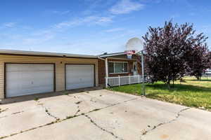 View of front of property featuring a porch, driveway, an attached garage, a front yard, and brick siding