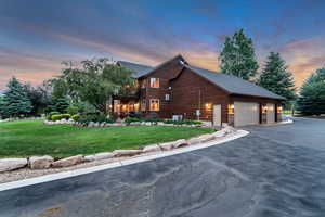 View of home's exterior featuring a lawn, a balcony, a garage, stone siding, and driveway