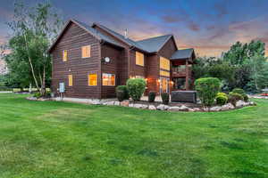 View of side of property featuring a yard, a hot tub, and a balcony